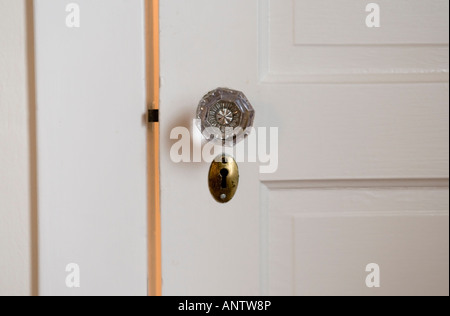 Antikglas Tür Knopf und Messing Schlüsselloch auf eine weiße Holztür Stockfoto