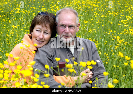 Schöne Senoir Paar genießt die Sonne auf einer grünen Wiese Feld voller Butterblumen Stockfoto