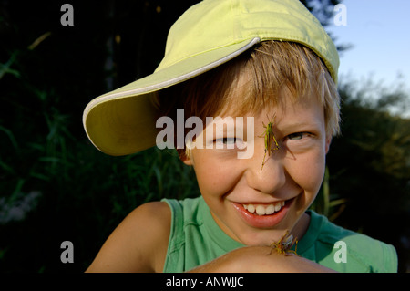 Junge, elf Jahre alte, mit einer Heuschrecke auf der Nase Stockfoto