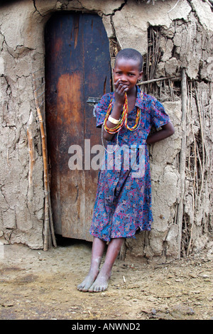 Maasai Mädchen außerhalb Dorf Lehmhütte Stöcken und Kuhmist Masai Mara National Nature Reserve Kenya gemacht Stockfoto