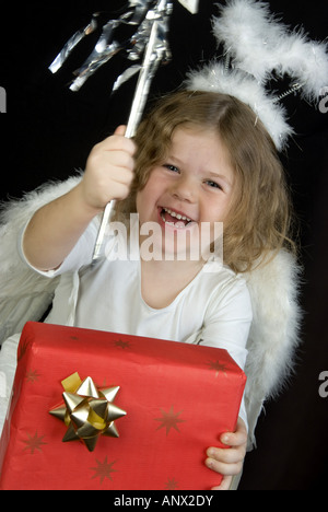 Mädchen wie ein Engel hält ein Weihnachtsgeschenk Stockfoto