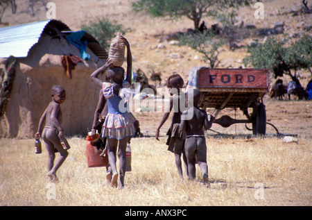 Dorfkinder Wassertragen in ländlichen Himba Dorf von Okohimu in Namibia, Afrika (MR) Stockfoto