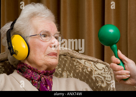 Ältere Dame tragen Ohr ^ Verteidiger und suchen ^ verärgert Stockfoto