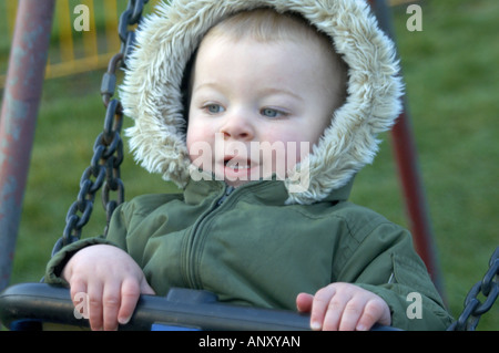 Ein ein-Jahr-altes Baby junge spielt auf einer Schaukel Stockfoto