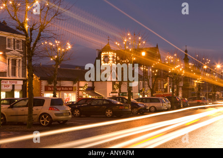 Abenddämmerung Weihnachtsbeleuchtung auf den Bäumen auf der High Street Moffat mit den Lichtspuren der Verkehr schneller vorbei an Schottland, Vereinigtes Königreich Stockfoto