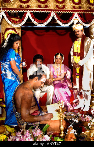 Traditionelle hinduistische Hochzeitszeremonie auf einer kunstvollen Bühne mit einem Priester, der heilige Rituale für die Braut und den Bräutigam Sri Lanka Ceylon vorführt. Stockfoto
