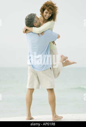 Älteres Paar, Mann, die Frau am Strand abholen Stockfoto