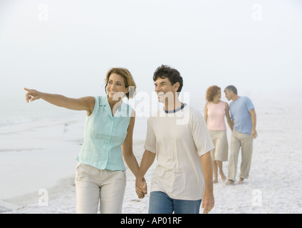 Älteres Paar zu Fuß am Strand, Frau zeigte auf Abstand Stockfoto