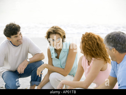 Zwei ältere Ehepaare hocken am Strand Stockfoto