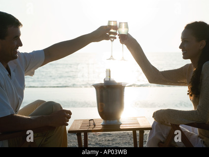 Junges Paar Klirren Champagner Gläser am Strand Stockfoto