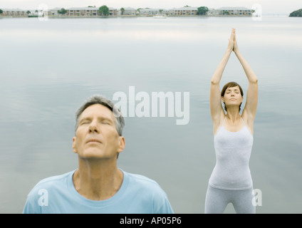 Paar Entspannungsübungen vom Rand des Wassers zu tun Stockfoto