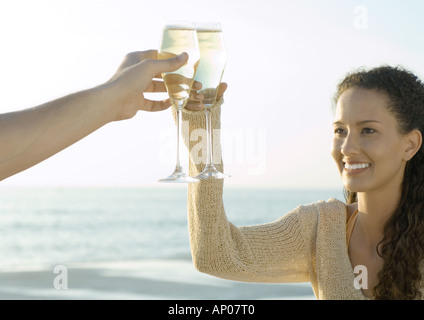 Paar klirrende Gläser Champagner, Meer im Hintergrund Stockfoto