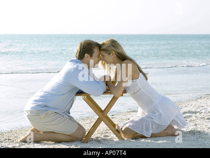 Paar am Strand, Kopf an Kopf kniend Stockfoto