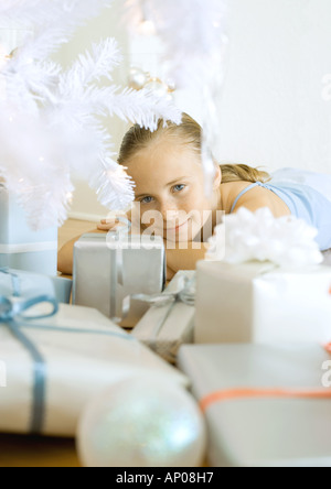 Mädchen liegend unter Weihnachtsbaum unter präsentiert Stockfoto