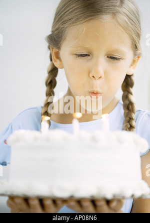 Kleines Mädchen hält Geburtstagstorte, Kerzen ausblasen Stockfoto