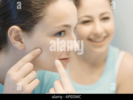 Teenager-Mädchen Gesicht berühren, während Freund Uhren Stockfoto