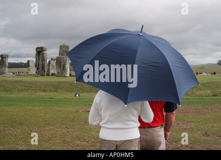 paar im Regen an Stonehenge, Wiltshire, England stehen Stockfoto