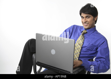 ANG200148 Executive lächelnd mit ungeraden Körperhaltung entspannt halten Laptop auf Schoß auf Stuhl sitzend Stockfoto