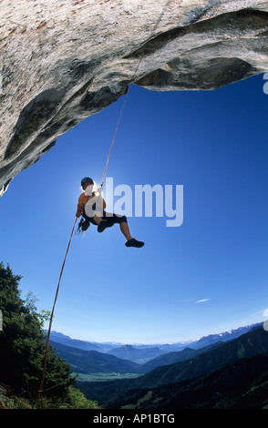 Rock Climber Abseilen nach unten aus einem Überhang des Gipfels der Kampenwand, Blick Richtung Tirol, Chiemgau, Bayern, Oberbayern, Stockfoto