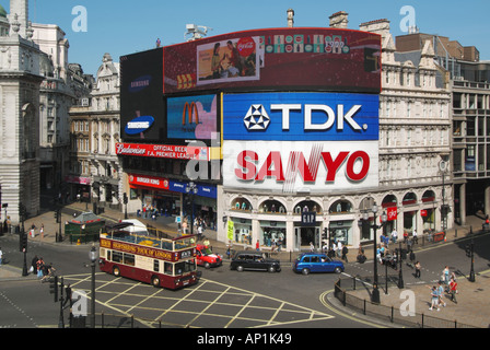 Mit Blick auf die oben offenen Tour Bus & Taxi überqueren, Ausfahrt am Piccadilly Circus mit beleuchteten Werbetafel West End London England Großbritannien Stockfoto