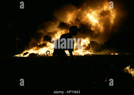 Der Junge geht am Lagerfeuer der 11. Nacht in Monkstown in Nordirland vorbei. In der Nacht vor dem 12. juli werden in loyalistischen Gebieten Brände angezündet Stockfoto