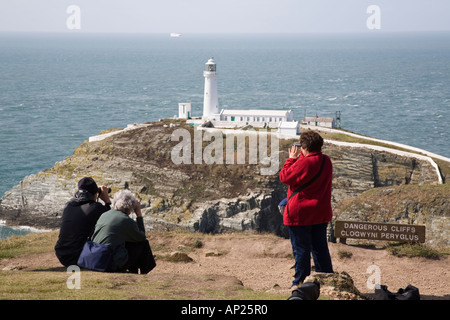 Vogelbeobachter mit dem Fernglas zu Meer beobachten auf Klippen mit South Stack Leuchtturm an der Küste. Holyhead heilige Insel Anglesey Wales Stockfoto