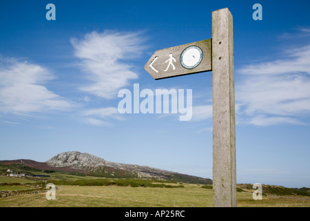 Insel von ANGLESEY COASTAL PATH Wegweiser gegen blauen Himmel mit Holyhead Mountain (Mynydd Twr) auf Holy Island, Anglesey, Wales, UK Stockfoto