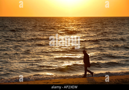 Eine Frau zu Fuß am Strand bei Sonnenuntergang, Wellfleet Hafen Sonnenuntergang, Cape Cod, Massachusetts, USA Stockfoto