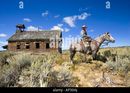 Cowboy mit Pferd am alten Schulhaus, Wildwest, Oregon, USA Stockfoto