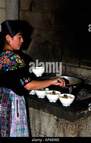 Mittelamerika, Guatemala, Aguas Calientes. Mutter gekleidet in traditioneller Handarbeit Textil Huipil Suppe kochen. Stockfoto