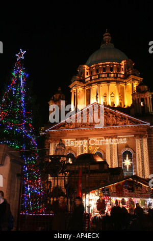 Glückliches Weihnachten Zeichen auf der Belfast City Hall mit kontinentalen Märkte auf dem Gelände zu Weihnachten, beleuchtet Stockfoto