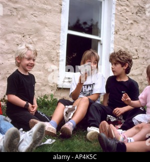Britische Kinder sitzen draußen im Garten in spielen ein Pass das Paket Spiel auf einer Geburtstagsparty in der 1980er in Wales Großbritannien KATHY DEWITT Stockfoto