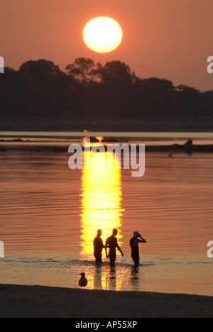Sonnenaufgang über Silhouette stehend Schwimmer im Wasser, Compo Strand, Westport, CT, USA. Stockfoto
