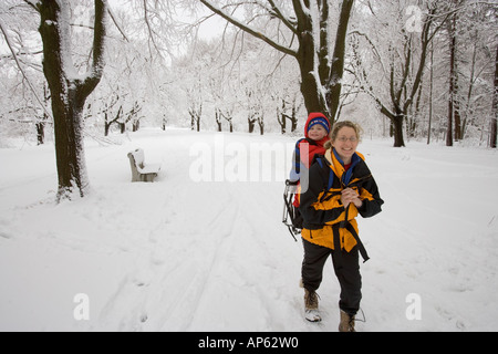 Eine Mutter trägt ihr kleiner Sohn auf einer Wanderung durch Neuschnee am Odiorne Point State Park in Rye, New Hampshire. Stockfoto