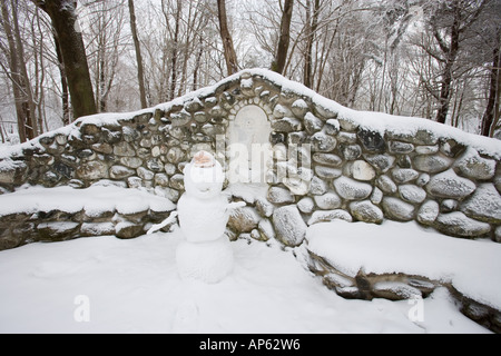 Ein Schneemann neben einer Steinmauer und Bänke im Odiorne Point State Park in Rye, New Hampshire. Stockfoto