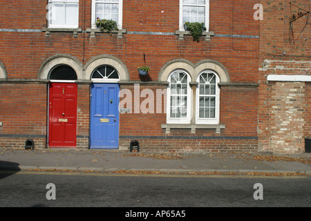 Zwei lackierte hell Haustüren in einer roten Ziegeln terrassenförmig angelegten Straße im Highworth Wiltshire Stockfoto