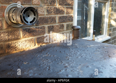 Alten rostigen Stahl inländischen Öltank gelegen neben Fenster, Schornstein und Wand- und nicht treffen Bauordnung erforderlich Stockfoto