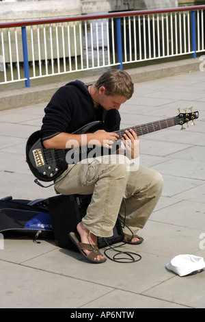 Student mit seiner e-Gitarre unterhaltsam Passanten Münzen auf der Themse laufen London Stockfoto