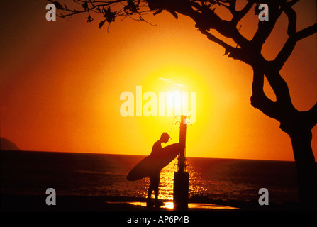 Surfer unter Stranddusche bei Sonnenuntergang Stockfoto