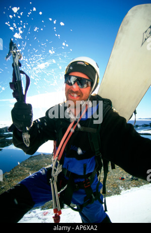 Snowboarder mit Eispickel Klettern Felswand mit Snowboard, Jim Lynn in der Antarktis Stockfoto