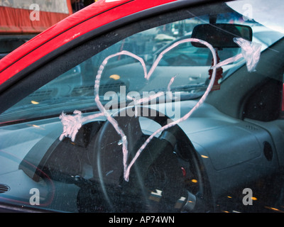 Rotes Herz und Amor Pfeil gezeichnet mit Lippenstift auf Autofenster Stockfoto