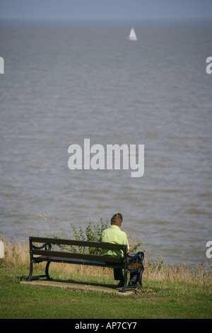 Einsamer Mann sitzt auf einer Bank am Meer, Frinton-on-Sea, Essex, England, UK. Stockfoto