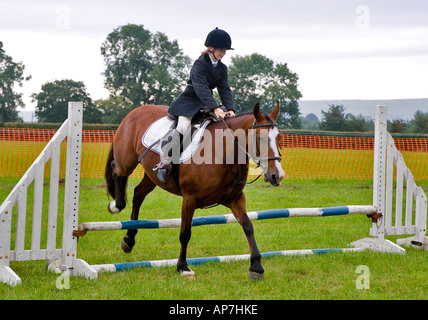 JUNGES MÄDCHEN AUF PFERD SPRINGEN ZAUN AN EINEM PFERD SHOW UK Stockfoto