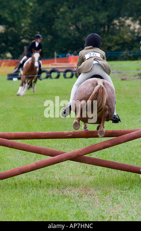 KLEINE MÄDCHEN AUF KLEINE PFERD VON HINTEN IN DER MITTE LUFT HORSE SHOW UK Stockfoto