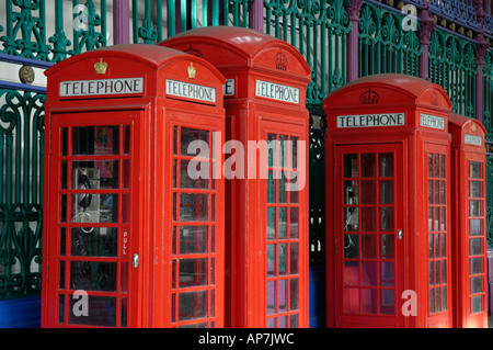 Vier traditionelle britische rote Telefonzellen gegen bunte viktorianische Schmiedearbeiten, London, England, UK Stockfoto