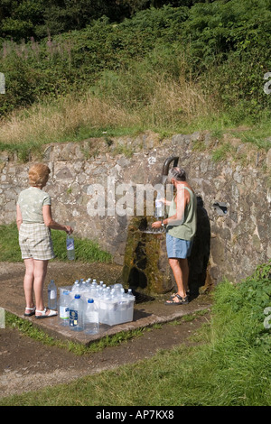 PAAR FÜLLEN PLASTIKWASSERFLASCHEN VOM FRÜHLING VON MALVERN WASSER AUF DIE MALVERN HILLS WORCESTERSHIRE ENGLAND UK Stockfoto