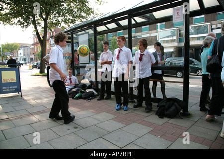 Schule Jungs spielen Fußball an Bushaltestelle Stockfoto