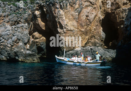 Gruppe von Personen in einem Boot in der Nähe einer Klippe Stockfoto