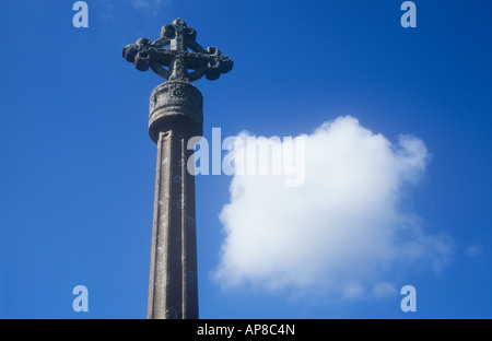 Flechten bedeckten Stein Keltenkreuz auf Steinsäule gegen den tiefblauen Himmel mit einzelnen quadratische weiße Kumuluswolke Stockfoto