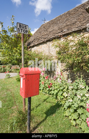 Einen roten Briefkasten und Stockrosen blühen neben einer alten Scheune der Cotswold bei Southend Farm, in der Nähe von North Nibley, Gloucestershire Stockfoto